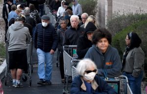 Shoppers in Las Vegas form a line around a Smiths Food & Drug as they wait for the store to open March 20, 2020.