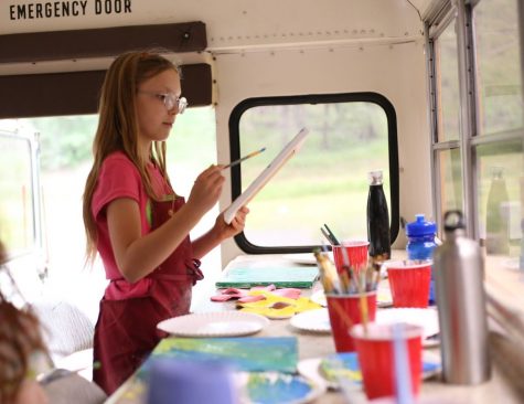 Nine-year-old Skylar paints a canvas to accompany the clay flower she created in a previous session aboard the School Bus Studio.
