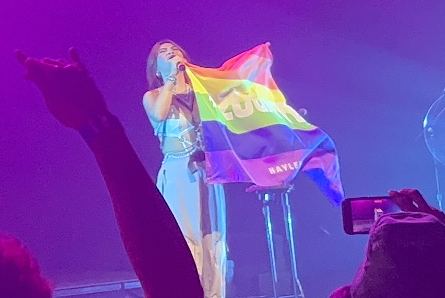 Hayley Kiyoko performing with a pride flag that had “#20GAYTEEN” written on it at The Met in Philadelphia on Aug. 19, 2022. 