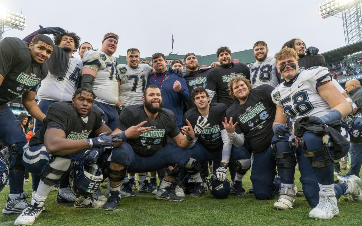 UConn players pose in celebration after their 27-14 victory over North Carolina at the 2024 Fenway Bowl, played Dec. 28 at Fenway Park. 