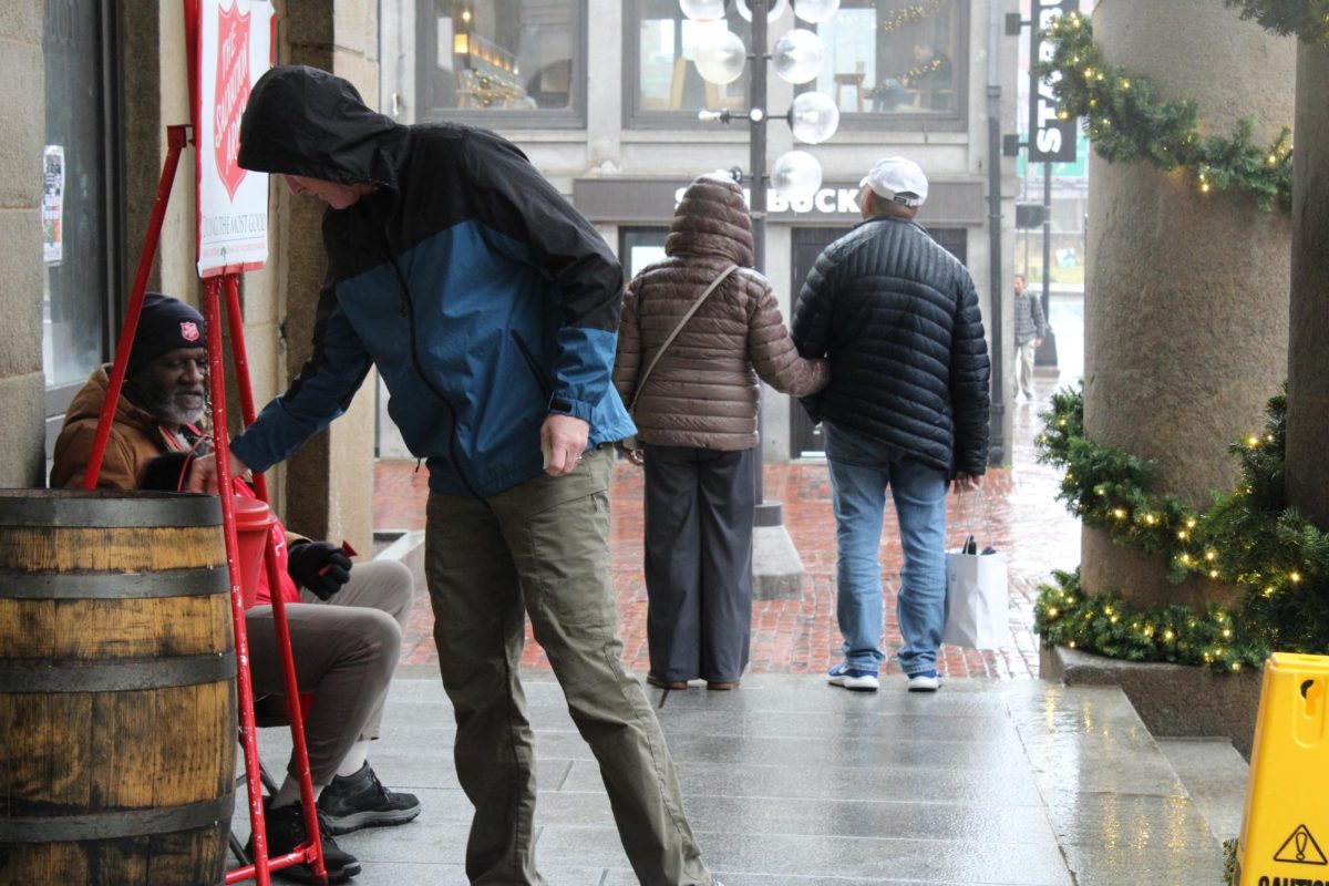 On a rainy day outside of Faneuil Hall in Boston, a passerby makes a heartwarming donation as a couple waits out the storm.